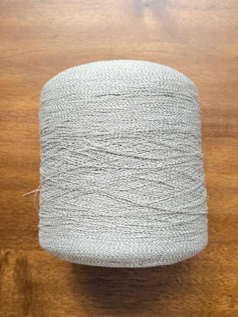 Ishikawa Safari Washi Blend Cone Yarn showcasing a soft white color in a cone shape on a wooden surface.