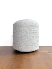 Ishikawa Safari Washi Blend Cone Yarn showcasing a soft white color in a cone shape on a wooden surface.