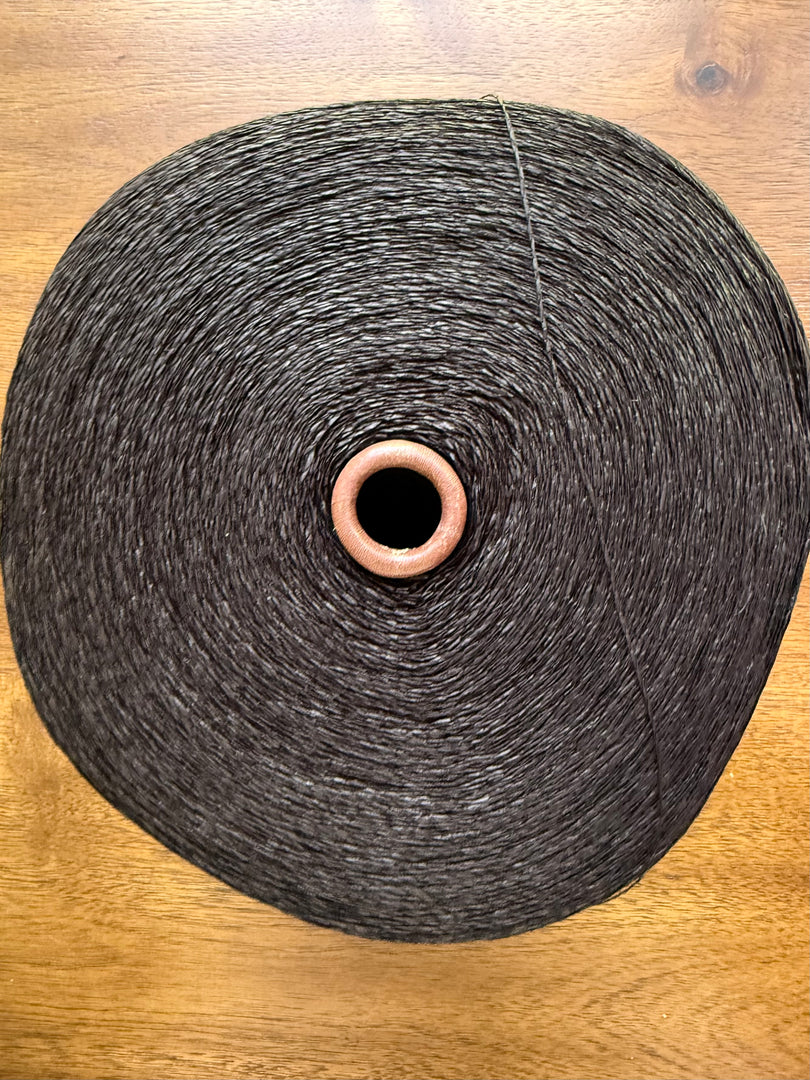 Maruyasu Techne 51 Paper 49 Modal Cone Yarn on a wooden table, showcasing its light color and smooth texture.