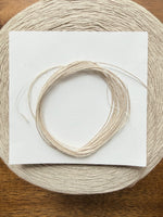 Load image into Gallery viewer, 100 Linen Cone Yarn displayed on a wooden surface, showcasing its natural texture and lightweight design.