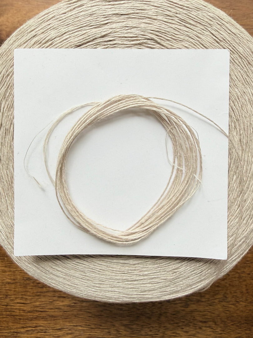 100 Linen Cone Yarn displayed on a wooden surface, showcasing its natural texture and lightweight design.