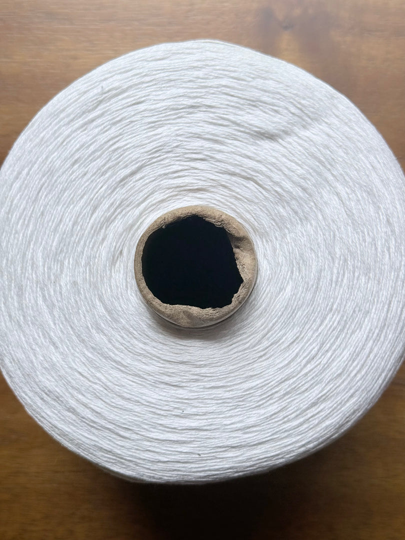 100 Linen Cone Yarn displayed on a wooden surface, showcasing its natural texture and lightweight design.