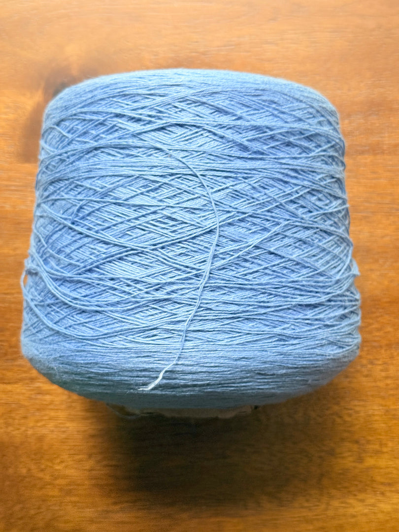100 linen Cone Yarn in light blue color, showcasing the texture and structure of the yarn cone.