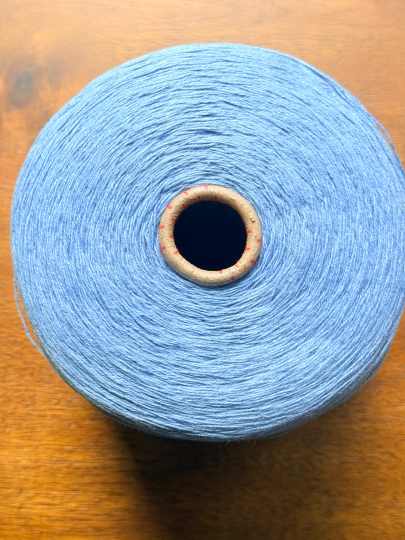 100 linen Cone Yarn in light blue color, showcasing the texture and structure of the yarn cone.