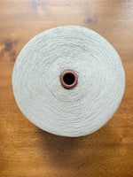 Load image into Gallery viewer, Maruyasu Techne 51 Paper 49 Modal Cone Yarn on a wooden table, showcasing its light color and smooth texture.
