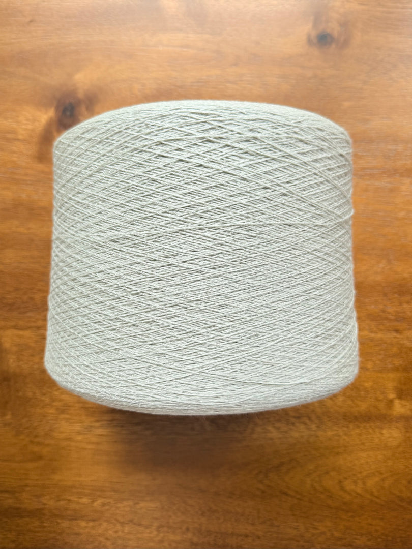 Maruyasu Techne 51 Paper 49 Modal Cone Yarn on a wooden table, showcasing its light color and smooth texture.