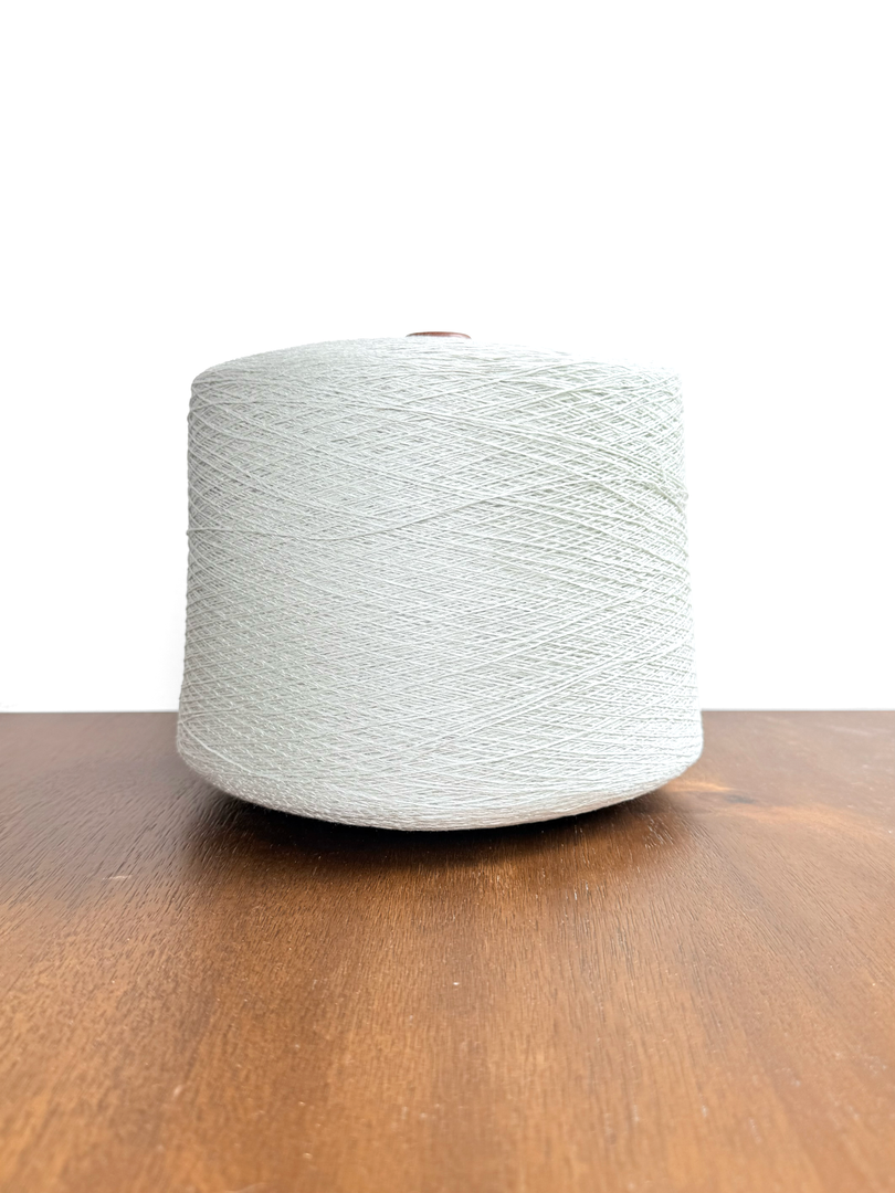 Maruyasu Techne 51 Paper 49 Modal Cone Yarn on a wooden table, showcasing its light color and smooth texture.