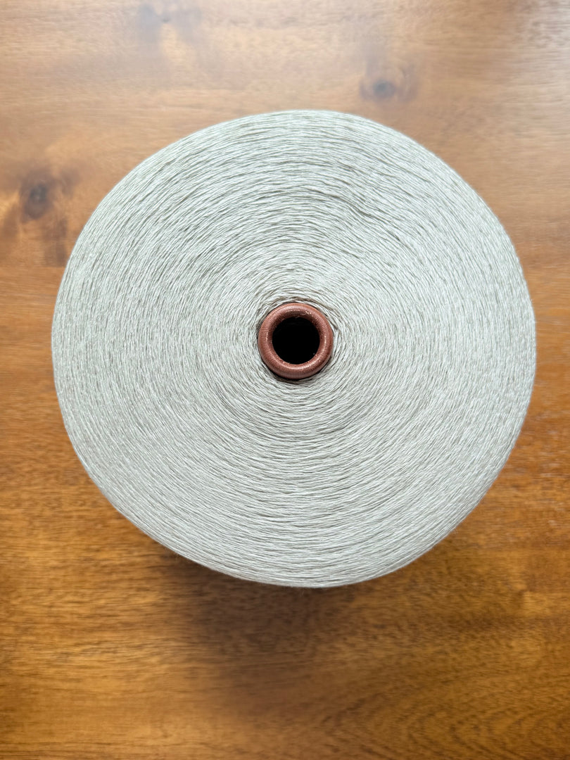 Maruyasu Techne 51 Paper 49 Modal Cone Yarn on a wooden table, showcasing its light color and smooth texture.