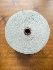 Maruyasu Techne 51 Paper 49 Modal Cone Yarn on a wooden table, showcasing its light color and smooth texture.