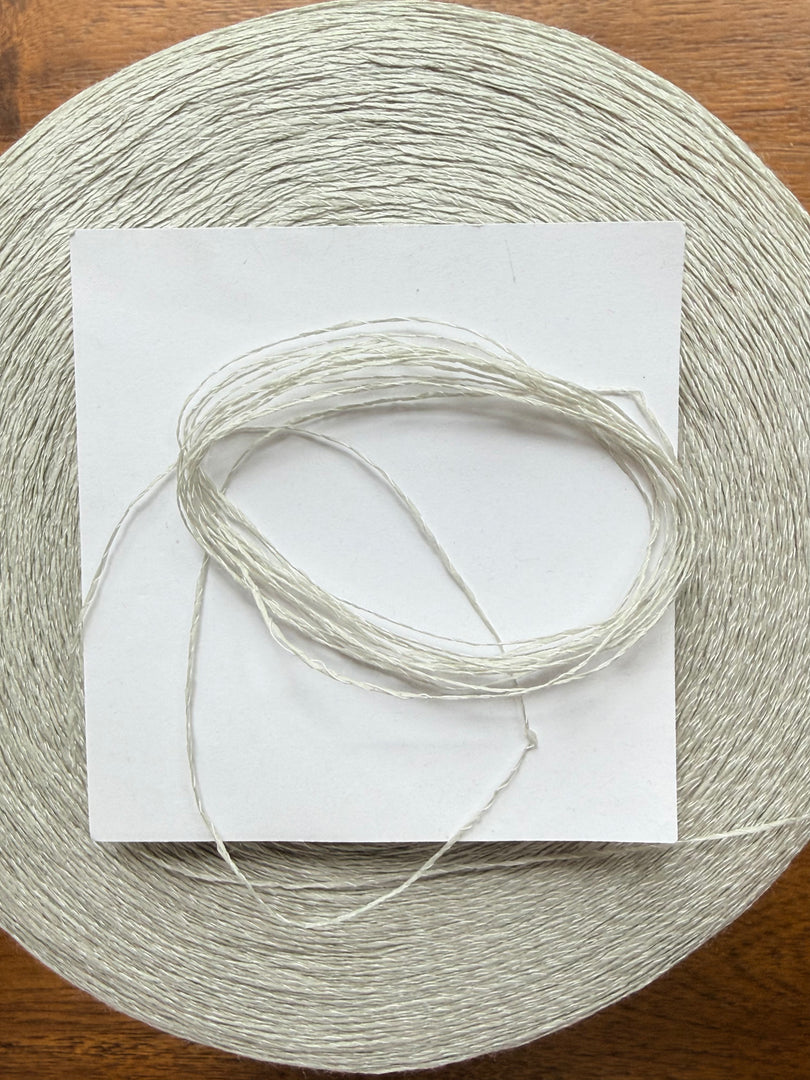 Maruyasu Techne 51 Paper 49 Modal Cone Yarn on a wooden table, showcasing its light color and smooth texture.